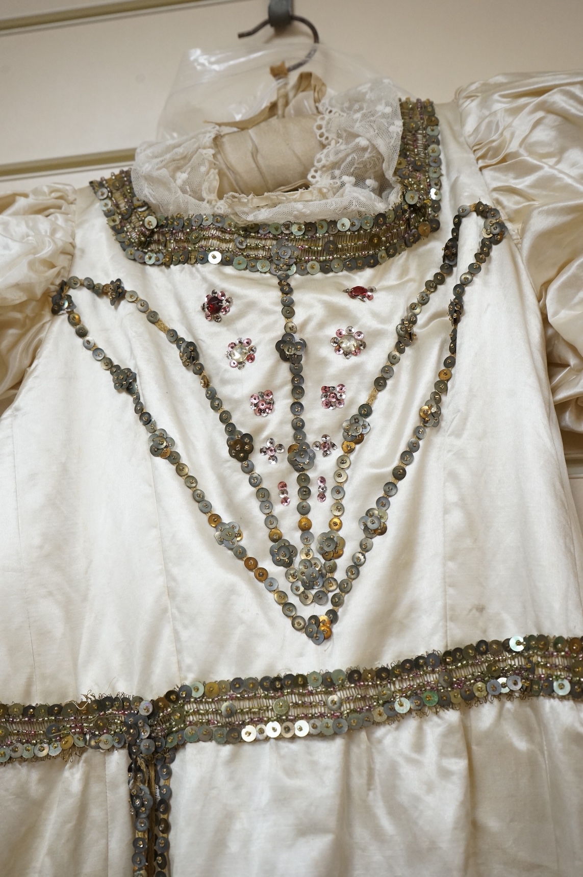 A cream silk satin theatrical costume, mounted with sequined braiding and pair of novelty shoes. Bust measurement 30inches.